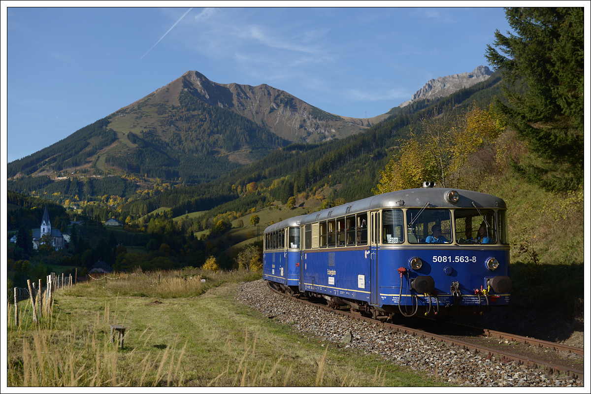 Die Laurentikirche in Vordernberg im Hintergrund und 5081.563 vor 5081.562 bei der Talfahrt der Erzberg Südrampe im Vordergrund am 13.10.2019.