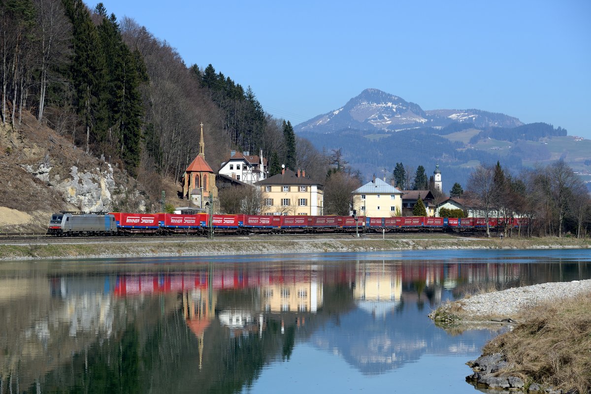 Die letzten Meter auf deutschem Boden legt die Railpool 186 288 mit ihrem 43139 zurück. Der Laufweg des sogenannten Winner-Zuges ist von Wuppertal nach Verona Quadrante Europa. Die Lok hat bereits  abgebügelt , da sich am Grenzübergang eine Trennstelle befindet. Der Inn lag zur Mittagszeit des 12. März 2014 ungewöhnlich ruhig da und ermöglichte die Spiegelung von Zug, Grenzabfertigungs-Gebäuden und der Otto-Kapelle, die an König Otto den I, König von Griechenland erinnern soll.
