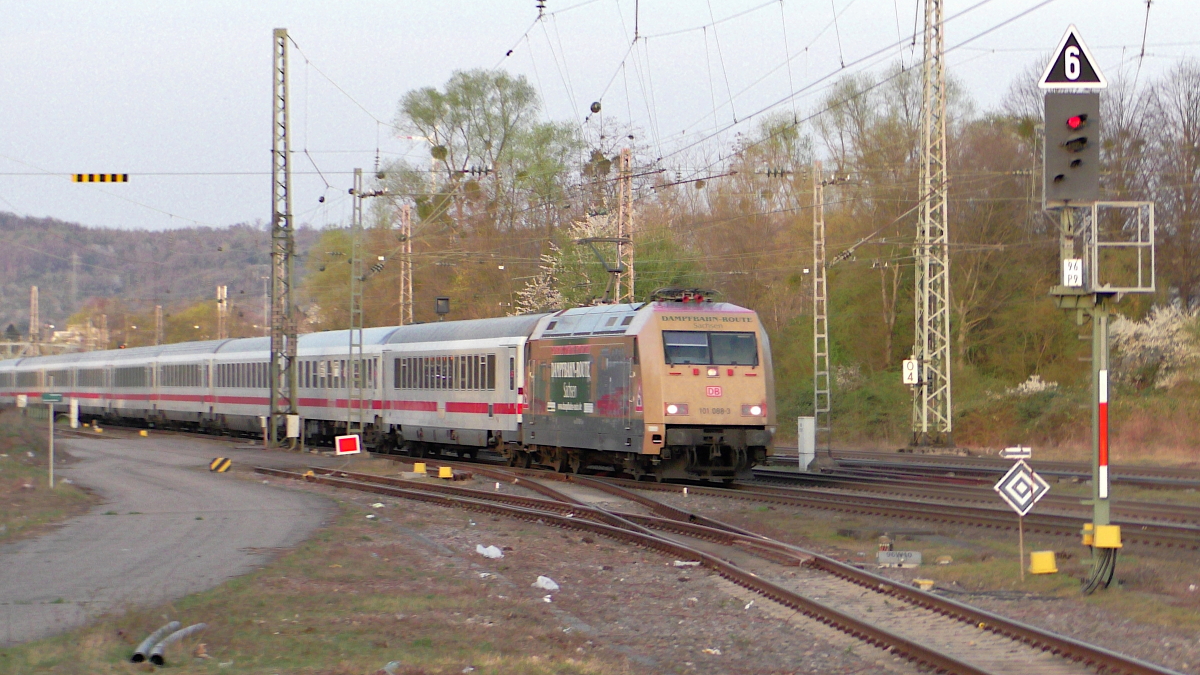 Die letzten Sonnenstrahlen sind gerade hinter den Bäumen verschwunden, als 101 088-3 mit Dampfbahn-Route Sachsen Beklebung und IC2183 am 28.03.2022 durch Karlsruhe-Durlach fährt.
