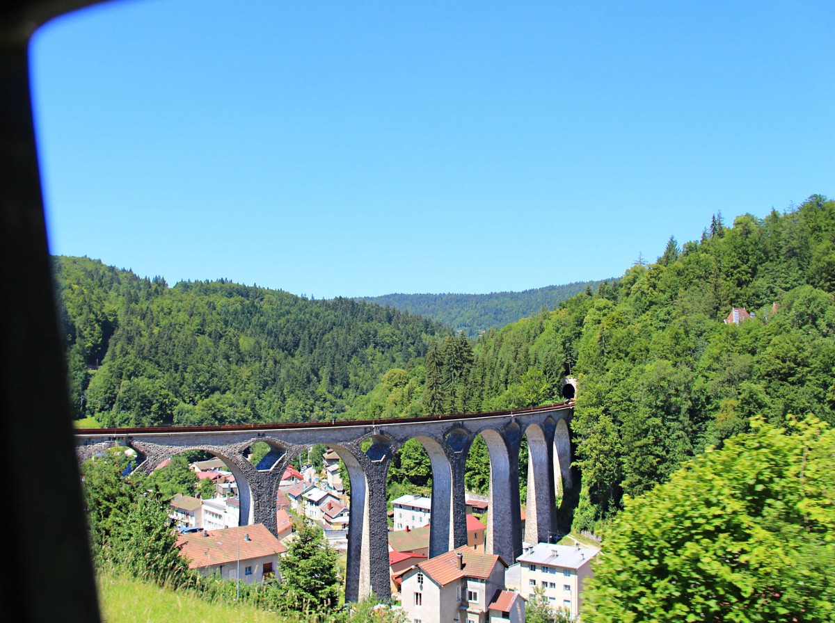 Die Ligne des Hirondelles: Beim Abstieg von Morbier kommt die imposante Ausfahrtsbrücke aus Morez in Sicht, über die der Triebwagen nach der dortigen Spitzkehre Richtung St.Claude weiterfahren wird. 30.Juni 2015. 