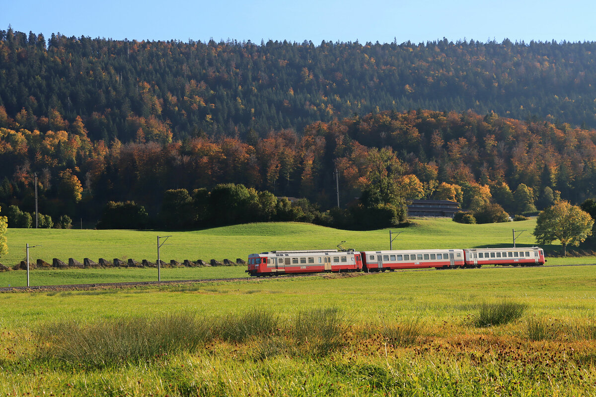 Die Linie durchs Vallée de Joux im Jura Gebirge: Gerade ist der abendliche Zusatzzug von hoch oben aus dem Vallée de Joux ins Tal heruntergekommen und fährt den im Jura überall auffallenden Panzersperren entlang. Der Zug besteht aus Triebwagen 567 174 (1983, ehemals Régional du Val-de-Travers 105, 2013 an TRAVYS) - Zwischenwagen 50 85 20-35 536 - Steuerwagen 50 85 80-33 375. Oberhalb Le Day, 19.Oktober 2021    