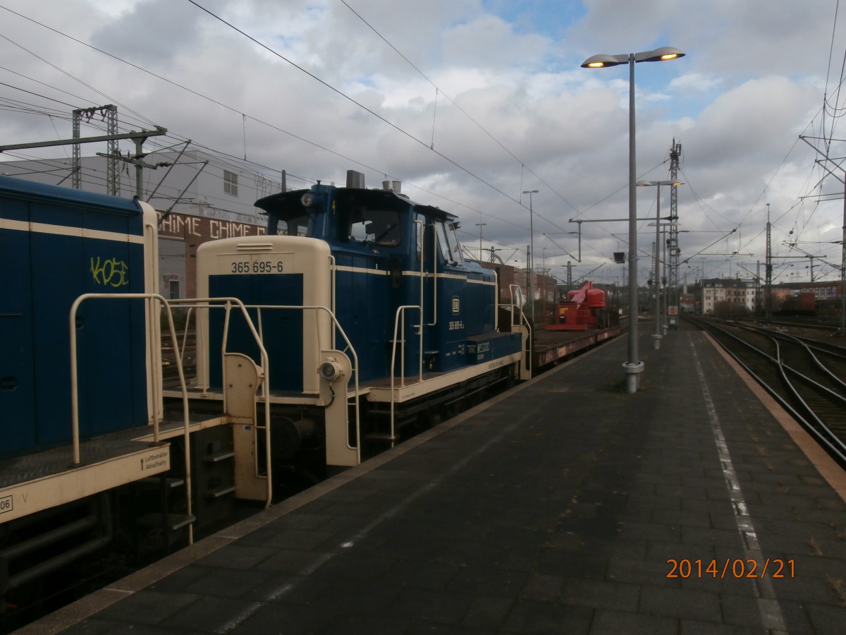 Die Lok 365 695-6 steht am 20.2.14 mit der Lok 261 671-2 und einen Flachwagen mit Hebebühne auf einen Abstellgleis in Düsseldorf HBF. 