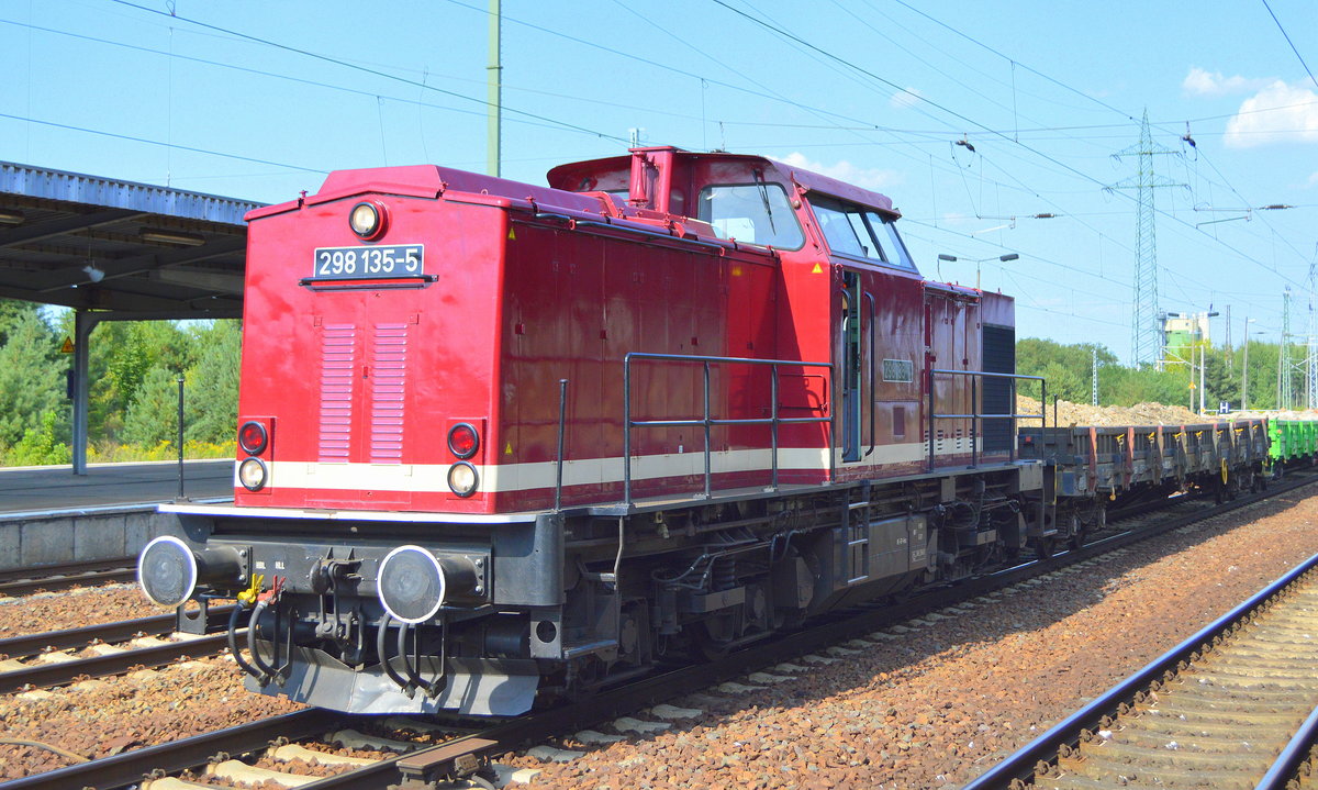 Die LOK OST - Lokführerdienstleistungen Olof Stille mit  298 135-5  [NVR-Nummer: 98 80 3298 135-5 D-OST] mit einigen Drehgestell-Flachwagen mit Bauschotter von der Baustelle am S-Bahnbetriebswerk Berlin Friedrichsfelde bei der Durchfahrt Bf. Flughafen Berlin-Schönefeld, 07.08.18
 