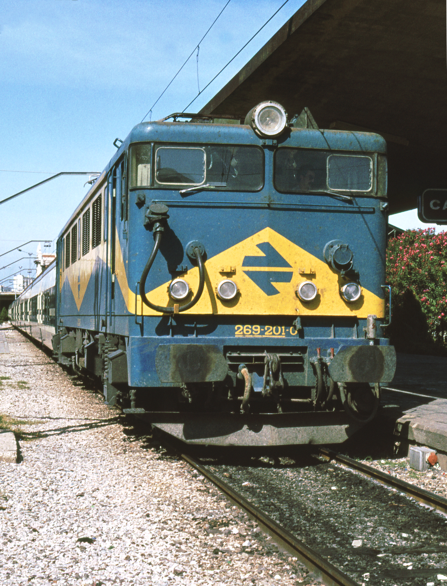 Die Lokomotive 269 201, Prototyp der Serie 269 201 bis 221, steht im Bahnhof von Cadiz, Endpunkt der Strecke Madrid - Cadiz. Um 13.35 wird sie mit dem modernen Talgo Pendular 113 nach Madrid Atocha abfahren, wo sie planmäßig um 21.27 eintreffen wird. Knappe 8 Stunden dauert die Fahrt über 727 km meist eingleisiger Strecke, nur die letzten 150 km ab Alcazar de San Juan waren damals zweigleisig. Oktober 1982.
Canon AE1, Canoscan, GIMP
