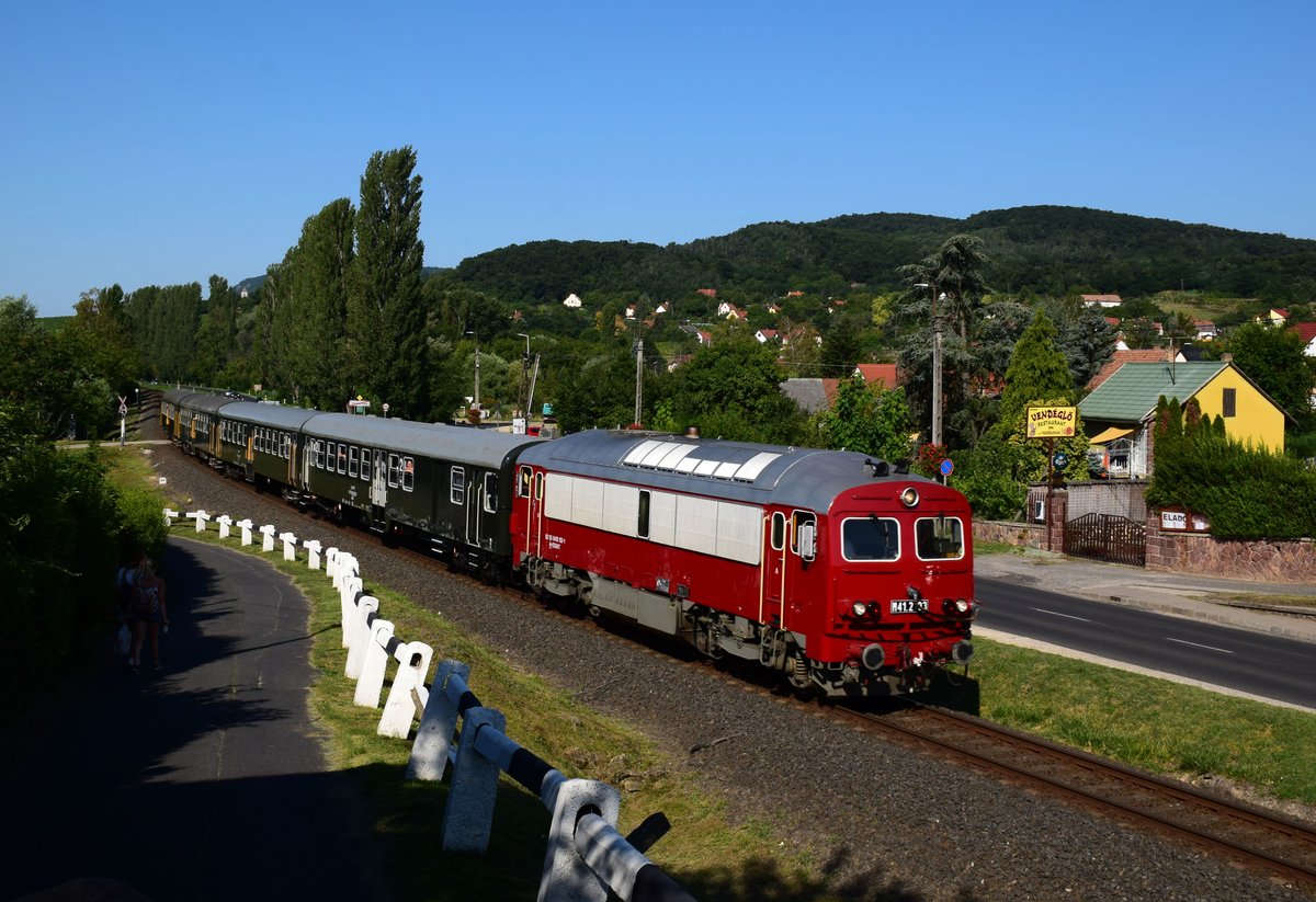 Die M41 2103 ist die älteste Lokomotive von der Reihe M41  Russel  Das Baujahr ist 1973.
Die Russel ist mit dem Zug 19747 (Tapolca-Balatonfüred). Der Wagensatz ist retro-lackierte.
Ábrahámhegy, 01.08.2020.