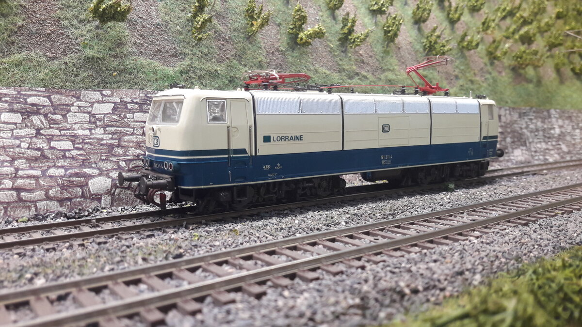 Die Mehrsystemlokomotive 181.2 wurde ab 1974 in einer Stückzahl von 25 Stück gebaut, als Nachfolgerin der Vorserie E320 ( Baureihe 181.0 u 181.1) und E410 ( BR 184) weiterentwickelt. Vorrangig für den Verkehr Deutschland - Frankreich u Luxemburg. Hier ein Modell in der nächsten Lackierung ( Ozeanblau/beige ), mit Schriftzug Lorraine. 4 Lokomotiven wurde so zusatzbezeichnet ( Lorraine, Saar, Mosel, Luxemburg ). Modell Roco 181 211-4 , 43692 DC digital