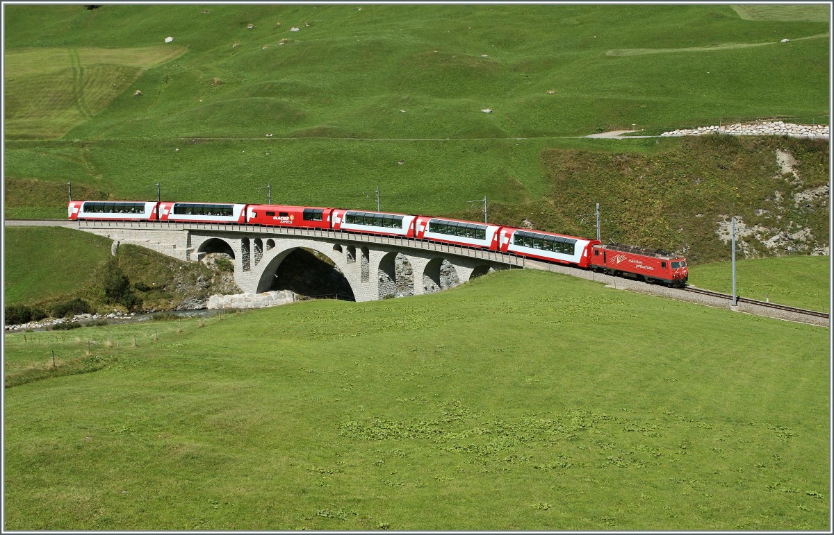 Die MGB HGe 4/4 N 105 mit dem Glacier Express 908 von Zermatt nach St. Moritz berquert kurz vor Hospental die Furkareuss. 
29. August 2013