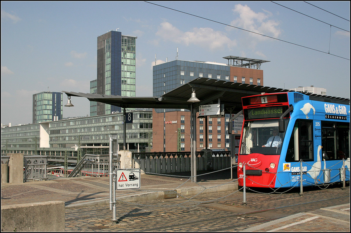 Die moderne Seite von Freiburg: 

der Hauptbahnhof. Die Straßenbahn überquert auf einer Brücke die Bahnsteiggleise. Von der Hoch-Haltestelle führen Treppen direkt zu den DB-Bahnsteigen. Im Bild ein Combino-Straßenbahnwagen der ersten Generation. 

11.05.2006 (M)