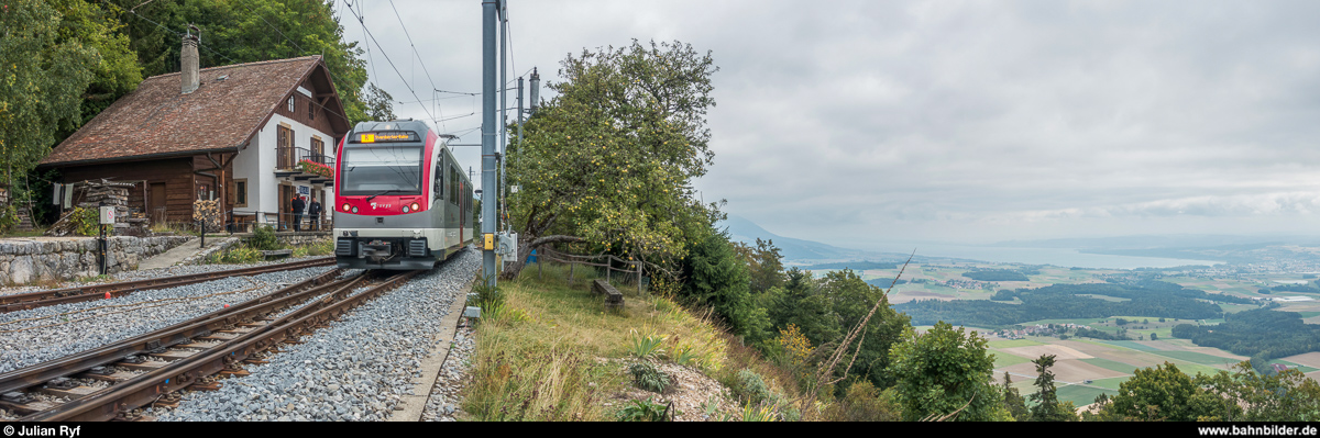 Die modernen Züge der YSteC passen nicht so richtig in die teilweise noch sehr urtümlichen Bahnhöfe. Hier am 2. September 2018 in Trois-Villes. Rechts unten ist der Neuenburgersee zu sehen mit dem Startpunkt der Bahn, Yverdon-les-Bains, ganz am rechten Bildrand.