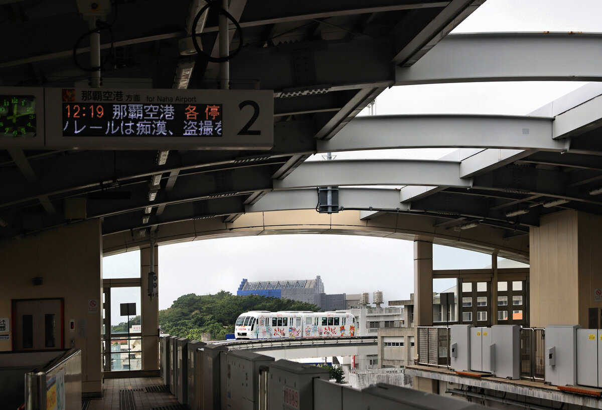 Die Monorail von Naha, Hauptstadt von Okinawa: Zug 1112 verlässt die Station Shuri. Shuri war einst das mächtige Zentrum von Okinawa, einem bedeutenden Handelsplatz, der wesentlich die Kontakte zwischen Japan und China steuerte und in dem die verschiedensten ostasiatischen Routen zusammenkamen. Das grosse Schloss Shuri ist 2019 vollständig niedergebrannt, im Hintergrund dieses Bildes sieht man die Gerüste für dessen Wiederaufbau. 22.April 2023  