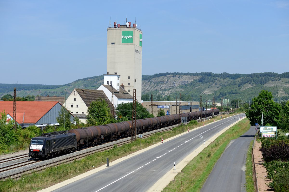 Die MRCE Dispolok ES 64 F4 211 fährt aktuell für die Rurtalbahn Cargo GmbH. Hier ist sie am 18. Juli 2014 mit einer Sonderleistung, bestehend aus Kesselwagen, in Karlstadt vor der markanten Kulisse des BayWa Lagerhauses zu sehen.