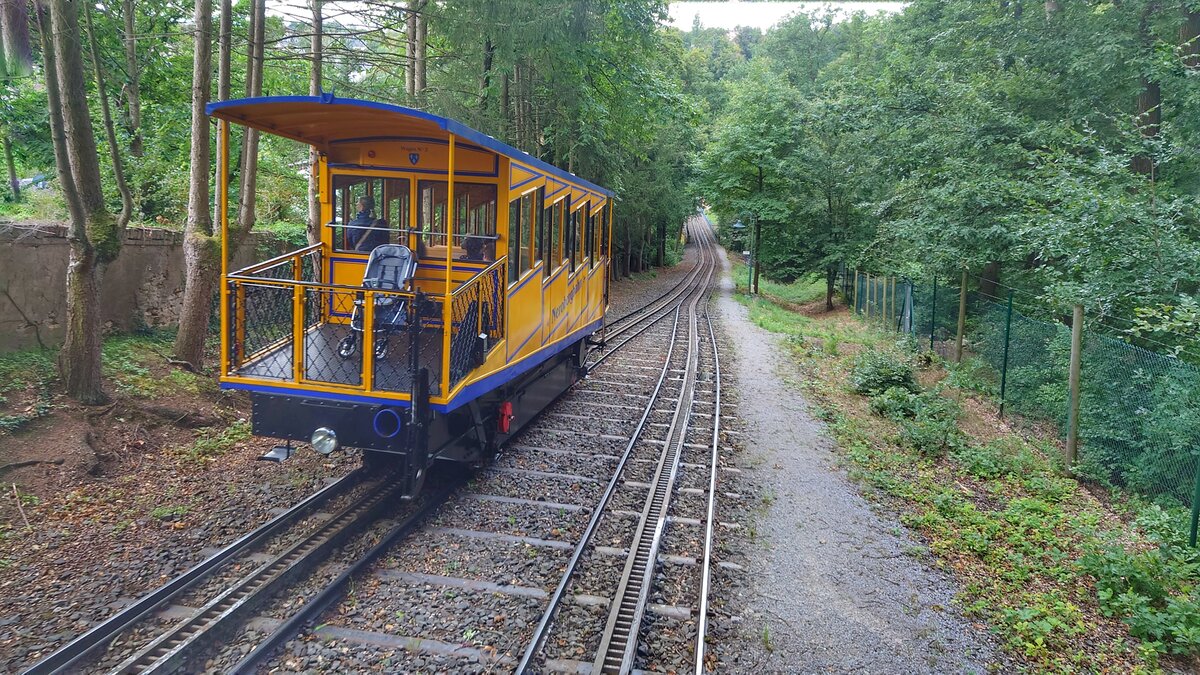 Die Nerobergbahn in Wiesbaden an der Ausweichstelle, wo die zweigleisige Ausführung mit gemeinsam genutzte Mittelschiene kurz aufgetrennt ist. Auch der blaue Einfüllstutzen für den Wasserballast unten rechts ist gut erkennbar. Aufnahme vom 31.8.23