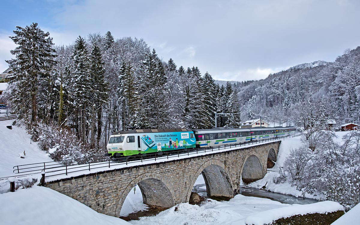 Die neue SOB Werbelokomotive Re 456 092 mit einer Werbung für Siemens fährt mit dem VAE über das Eisenbahnviadukt in Kaltbrunn.Bild Januar 2017