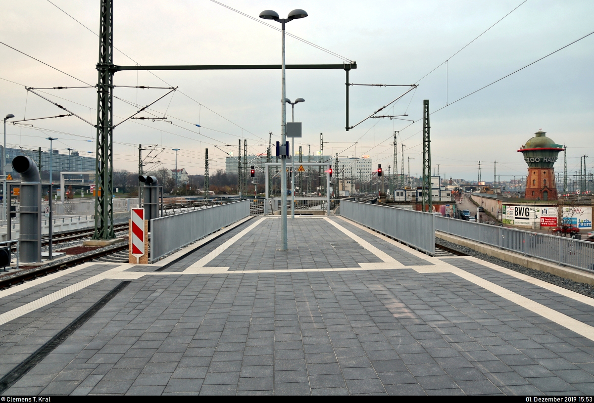 Die neue Westseite in Halle(Saale)Hbf: ein Rundgang (Bild 23)
***
Am ersten Adventssonntag wurden im Knoten Halle (Saale) die Bahnsteige 4/5 und 6/7 samt neuem Sanitärbereich und denkmalgerecht rekonstruierten Arkaden feierlich wiedereröffnet. In einer kleinen virtuellen Führung möchte ich Euch die modernisierten Anlagen vorstellen.

Im Gegensatz zur Ostseite verfügen die Bahnsteige der Westseite über einen zusätzlichen Treppenaufgang, der zur Straßenbahnhaltestelle bzw. Richtung Innenstadt führt.
Damit spart man sich den kleinen Umweg über das Empfangsgebäude und den Hans-Dietrich-Genscher-Platz (Bahnhofsvorplatz).
Hier kann man den Zu- bzw. Ausgang auf Bahnsteig 6/7 mit dem im Jahr 2008 sanierten, für den Bergzoo Halle werbenden Wasserturm im Hintergrund sehen.

[1.12.2019 | 15:53 Uhr]