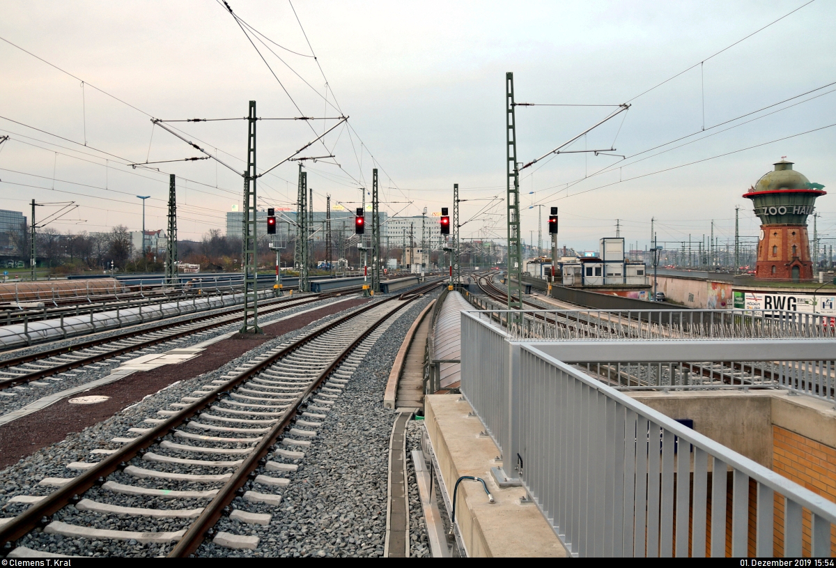 Die neue Westseite in Halle(Saale)Hbf: ein Rundgang (Bild 24)
***
Am ersten Adventssonntag wurden im Knoten Halle (Saale) die Bahnsteige 4/5 und 6/7 samt neuem Sanitärbereich und denkmalgerecht rekonstruierten Arkaden feierlich wiedereröffnet. In einer kleinen virtuellen Führung möchte ich Euch die modernisierten Anlagen vorstellen.

Am Ende des Bahnsteigs 6/7 darf ebenso ein Blick auf die nördliche Ausfahrt nicht fehlen. Während am rechten Rand der im Jahr 2008 sanierte und für den Bergzoo Halle werbenden Wasserturm steht, kann in der Ferne (Bildmitte) das mittlerweile stillgelegte elektromechanische Stellwerk Hp 4, Bauart 1912 von Siemens&Halske, auf dem Gleisvorfeld erspäht werden.
Die Inbetriebnahme dieses Gleisbildstellwerks von WSSB fand im September 1975 statt. Bis zum Morgen des 28.11.2019 war der dortige Fahrdienstleiter (Fdl) noch für den Zugbetrieb der Gleise 1a, 1 und 2 (künftig 1–3) zuständig, ehe dort die Umbaumaßnahmen beginnen (später dazu mehr).

[1.12.2019 | 15:54 Uhr]