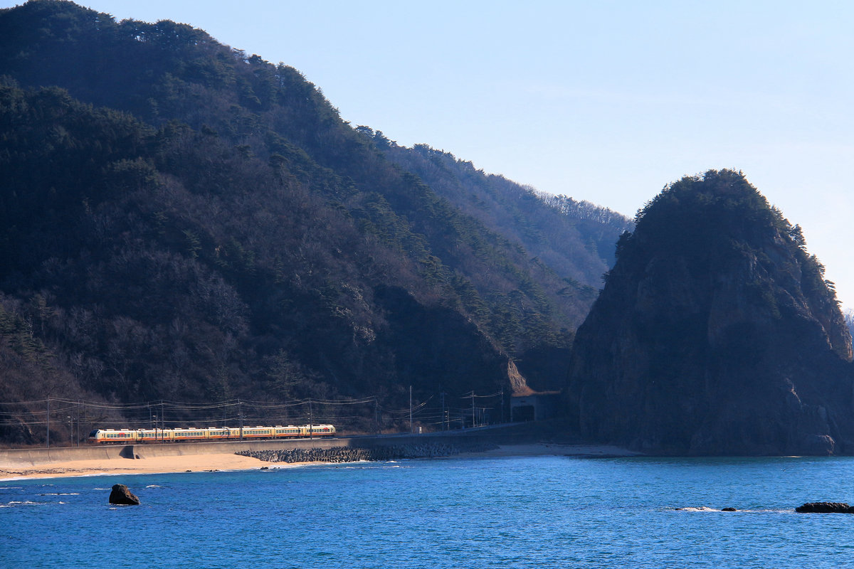 Die Nordwestküste Japans, Hauptlinie Niigata - Akita am Japanischen Meer: Ein Expresszug Serie 653 in der grandiosen Küstenlandschaft bei Echigo Kangawa/Wakigawa. 18.März 2019 