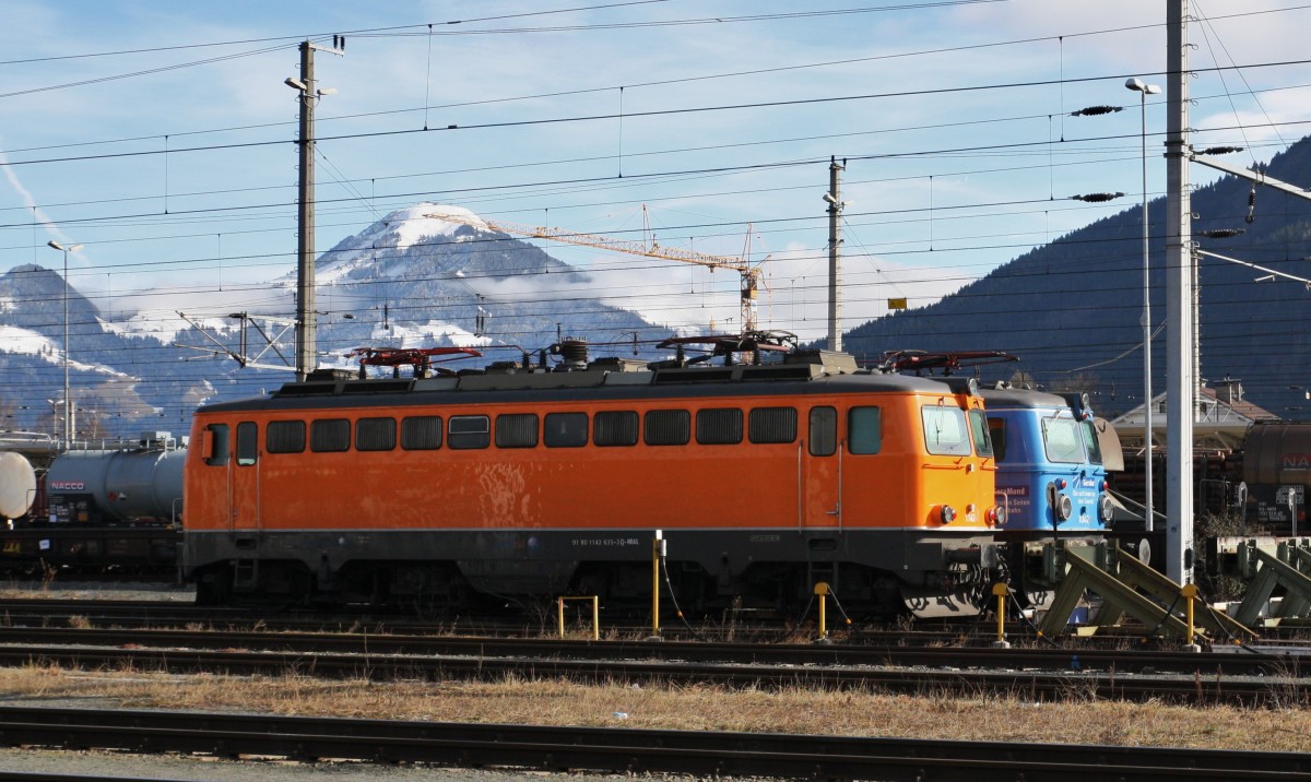 Die orange 1142 635-3 und die 1042 520-8 ``Lokmagazin`` stehen am 8.2.2014 im Bahnhof Wörgl. Beide kamen mit Skisonderzügen nach Tirol und fuhren am Abend wieder zurück. Eine der beiden fuhr mit dem DRV nach Utrecht. Im Hintergrund sieht man das Skigebiet von Hopfgarten und Söll.