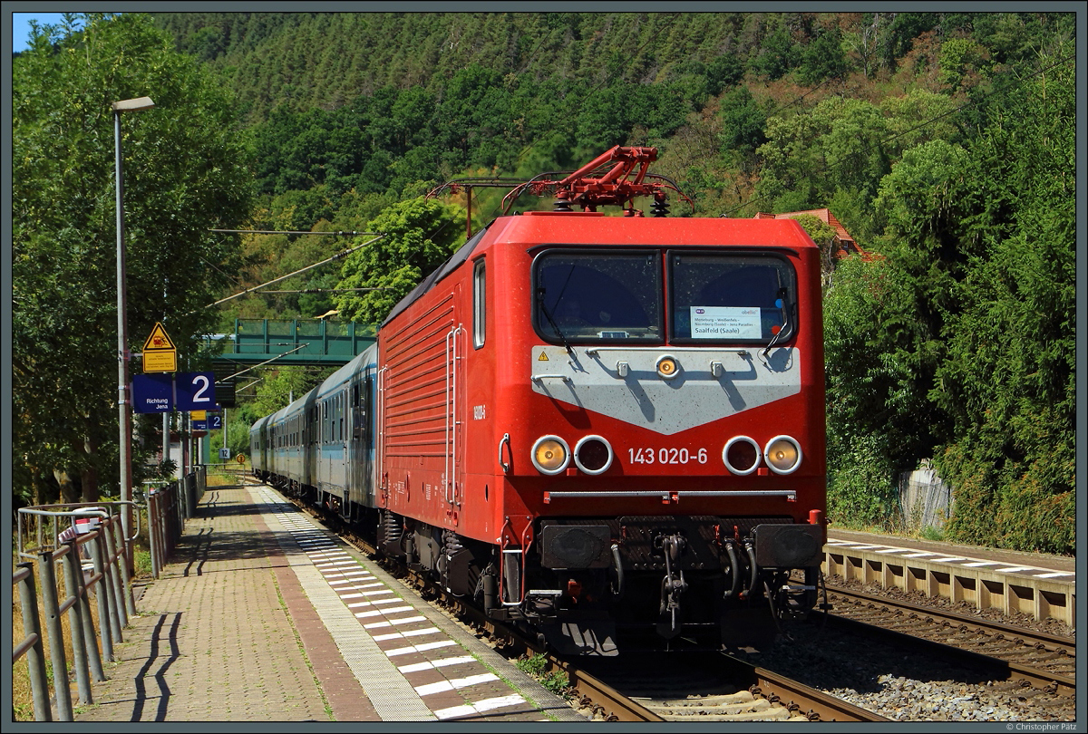 Die orientrote 143 020-6 der SRS hält am 06.08.2022 mit ihrem Ersatzzug in Uhlstädt. 