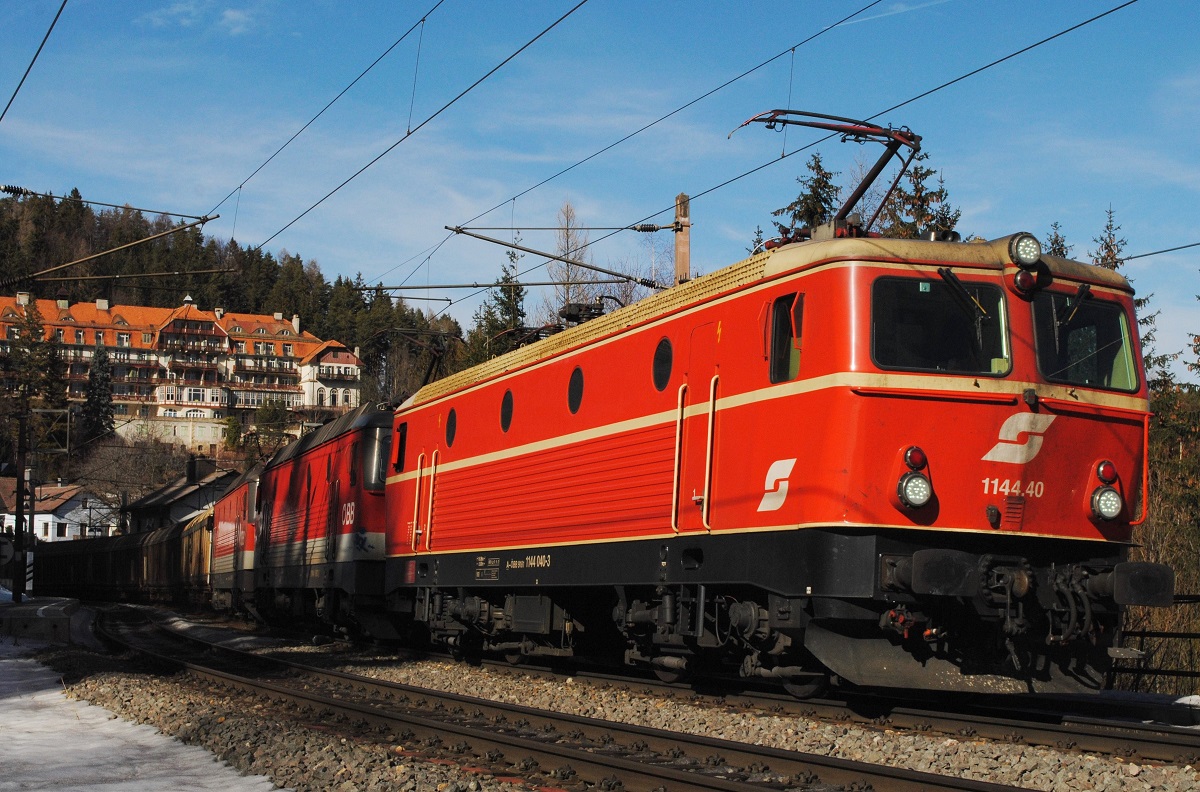 Die im Originallook der 1980er Jahre gehaltene 1144 040 und zwei weitere Loks der Reihe 1144 ziehen einen Güterzug durch die Haltestelle Wolfsbergkogel und werden in wenigen Minuten den Bhf. Semmering erreichen. (16.02.2019)