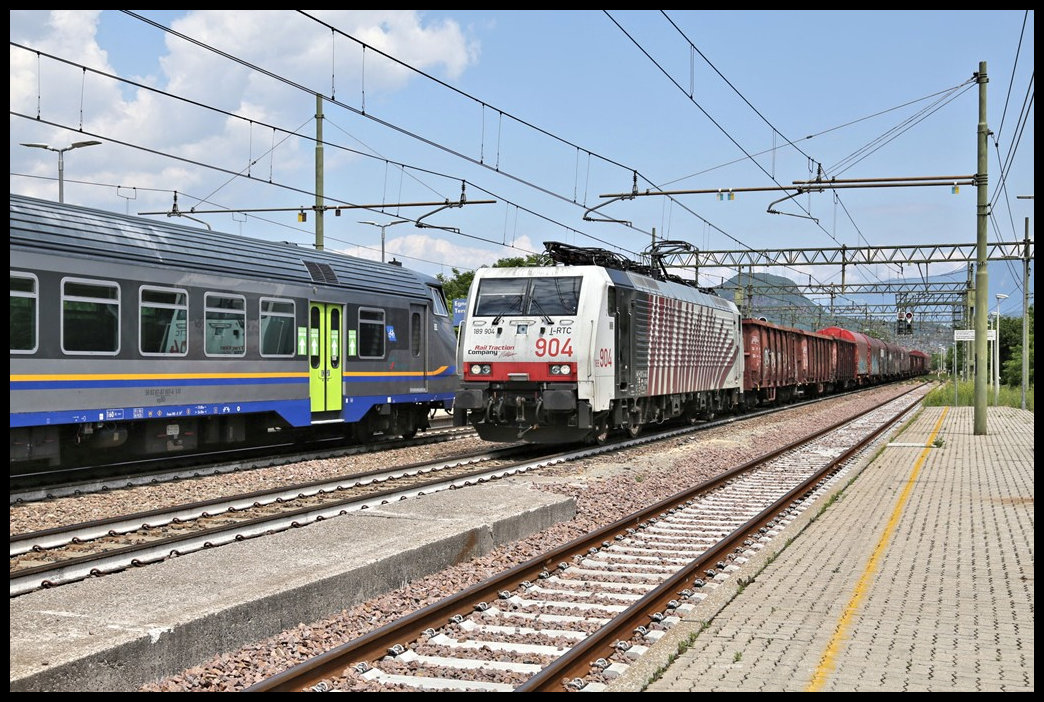 Die private Rail Traction 189904 passiert hier am 31.5.2022 auf dem Weg in Richtung Trento auf der Brennerbahn im Bahnhof Egna / Neumark einen entgegen kommenden Regionalzug.