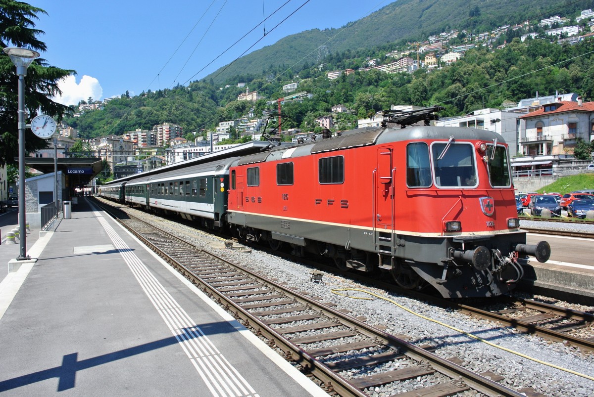 Die Re 4/4 II 11215 hat soeben zwei ex. Bpm51 angekuppelt, und wird in Krze mit diesen beiden Zusatzwagen den IR 2182 in Locarno bernehmen, 17.07.2014.