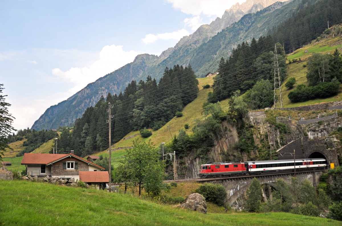 Die Re 4/4 II 11300 befindet sich mit ihrem Schnellzug auf dem Weg in Richtung Norden und überquert soeben die untere Wattinger-Brücke. Links im Bild ist das ehemalige Bahnwärterhaus 23cs zu sehen, welches vor ein paar Jahren in ein Wohnhaus umgebaut wurde. 26.07.2015