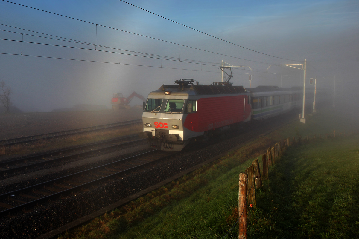 Die Re 446 015 der SOB zieht den Voralpenexpress frühmorgens aus dem dichten Nebelmeer raus ans Sonnenlicht,dabei ist ein Teil des Radiuses eines sehr selten zu sehenden Nebelbogens vor der Lok zu bewundern.Bild Kaltbrunn 1.11.2014