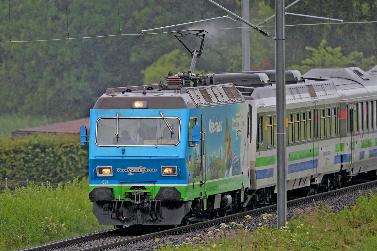 Die Re 456 091 unterwegs mit dem Voralpenexpress nahe Bollingen bei starkem Regen am 29.6.2014