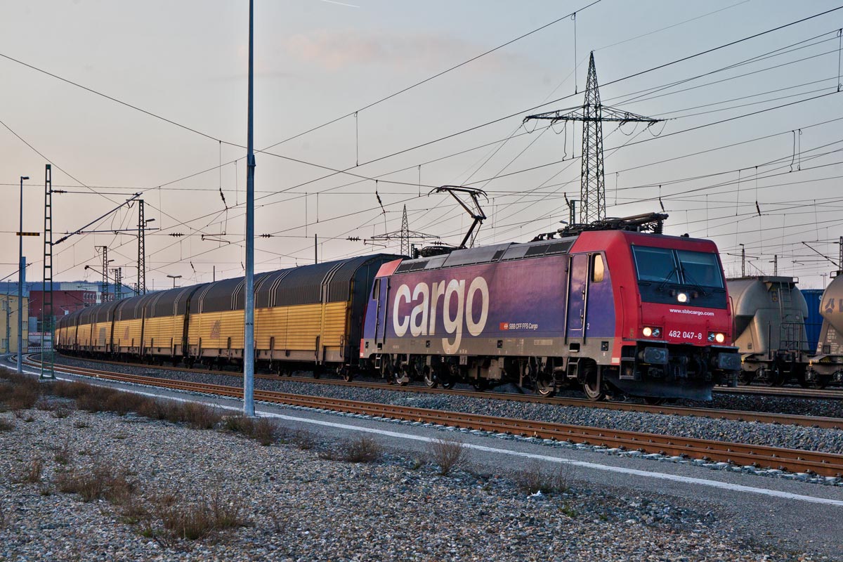 Die Re 482 047-8 fährt mit einem ARS Altmann Autozug in den Abendstunden des 13.3.2016 in Würzburg vorüber.