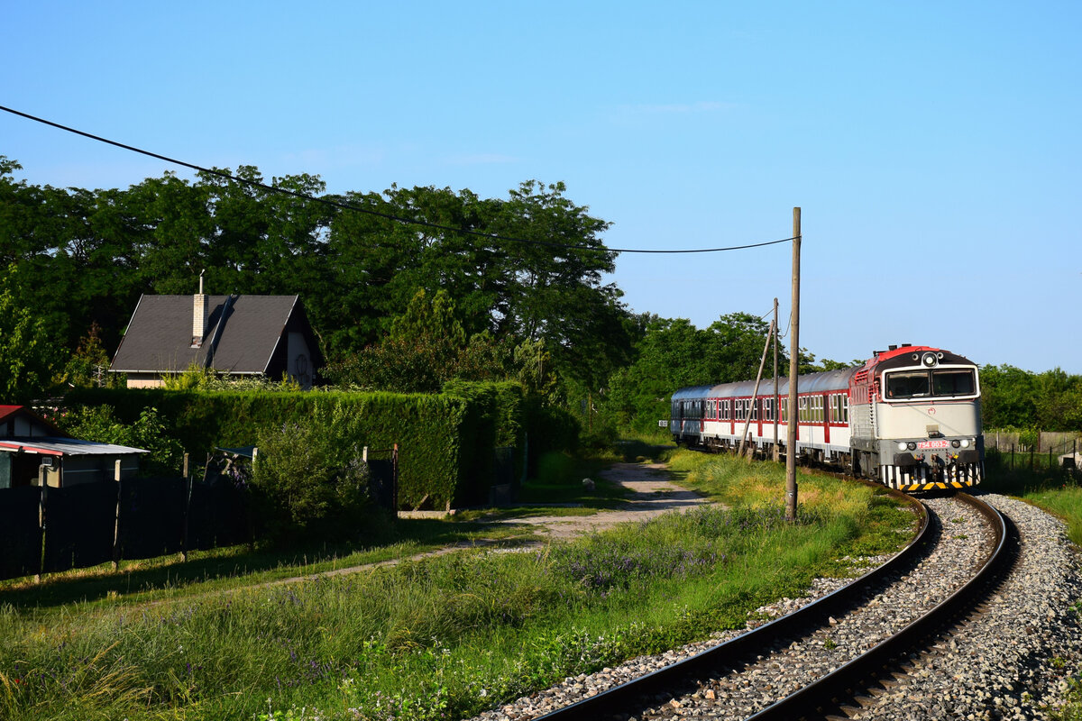Die retrolackierte 754 003 mit dem Abendzug 4342 von Komárno (Komárom) nach Dunajská Streda (Dunaszerdahely) kurz vor Komárno Nová Stráž (Örsújfalu). 13.06.2023.