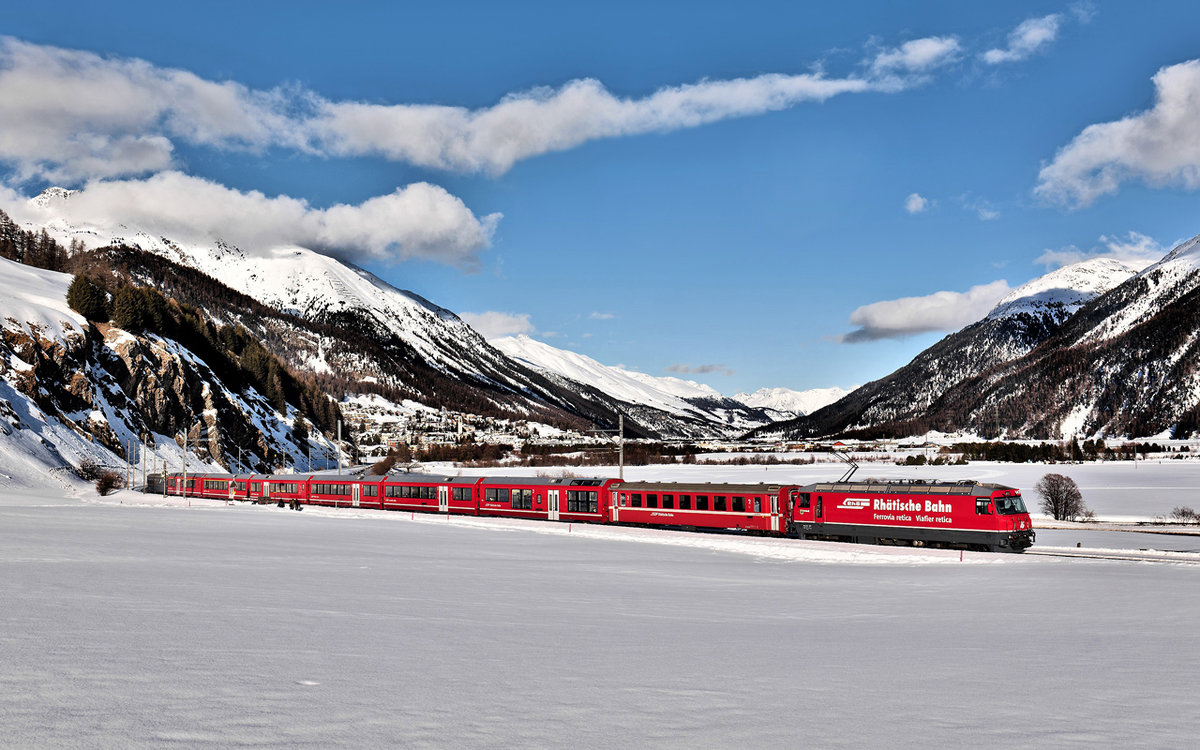 Die RhB Ge 4/4 III 647  Grüsch  fährt bei bestem Wetter in Celerina mit dem IR 1141 nach St.Moritz vorüber.Bild 27.1.2018