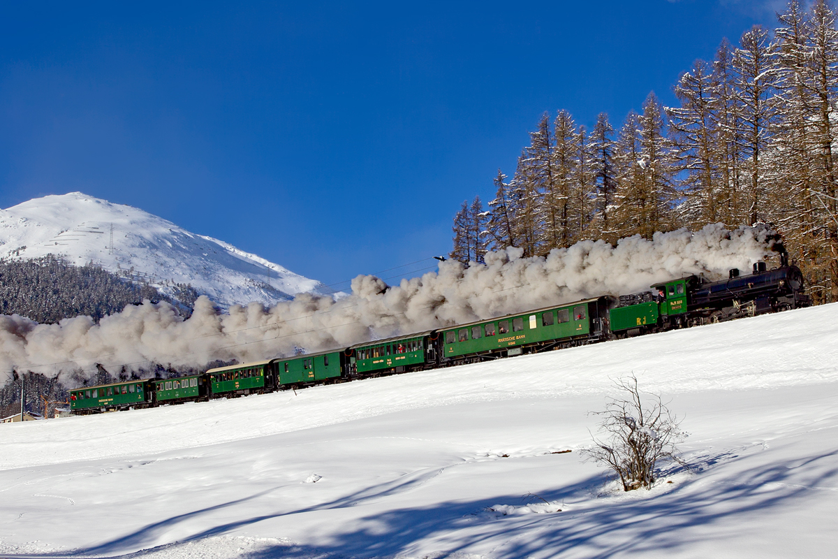 Die RhB Schmalspurdampflokomotive G 4/5 108 dampft in der eisigen Luft des Engadins in Susch mit einem Nostalgiezug von Samedan nach Scuol  vorüber.Bild 24.Januar 2015