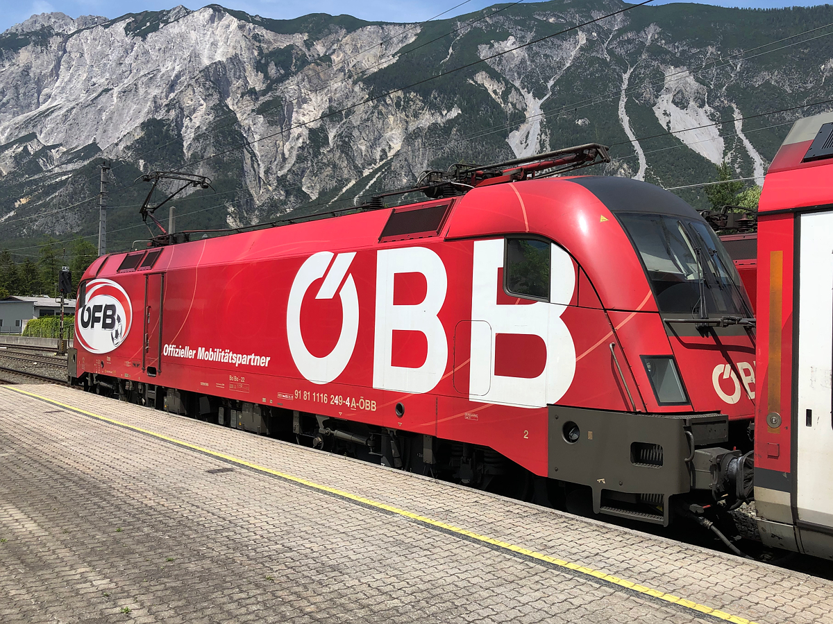 Die Rückseite der 1116 249 im  ÖFB  Design mit Tschirgant im Hintergrund am Zugschluss des RJX 867. Ötztal-Bahnhof am 16.06.2021