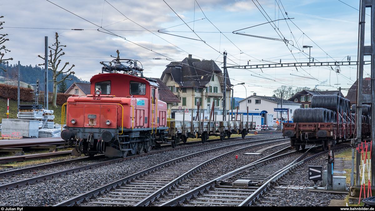 Die RUWA Drahtschweisswerk AG in Sumiswald besitzt zwei Ee 3/3, welche sie für die Überfuhr der von SBB Cargo in Sumiswald-Grünen angelieferten Güterwagen zu ihrem Werk im Ortsteil Burghof an der nicht mehr für den Personenverkehr genutzten Strecke Richtung Wasen nutzt. Da die Entladerampe im firmeneigenen Anschlussgleis nur Platz für zwei Wagen bietet, werden die Wagen im Bahnhof Sumiswald-Grünen gelagert und von der Ee 3/3 jeweils paarweise ins Werk zum Entlad und danach gleich wieder zurück gebracht. Ich habe den morgendlichen Wagenwechsel am 20. Februar 2020 fotografisch dokumentiert.<br>
Die hier im Bahnhof Sumiswald-Grünen abgestellte Ee 3/3 16403 von 1945 ist bereits einige Jahre bei der RUWA im Einsatz. Es ist zu vermuten, dass sie durch die neu übernommene Ee 3/3 16408 von 1946 überflüssig geworden ist und wohl bald ausgemustert wird. Rechts steht ein am Vorabend eingetroffener Ganzzug mit Drahtrollen, welche an diesem Tag ins Werk müssen.