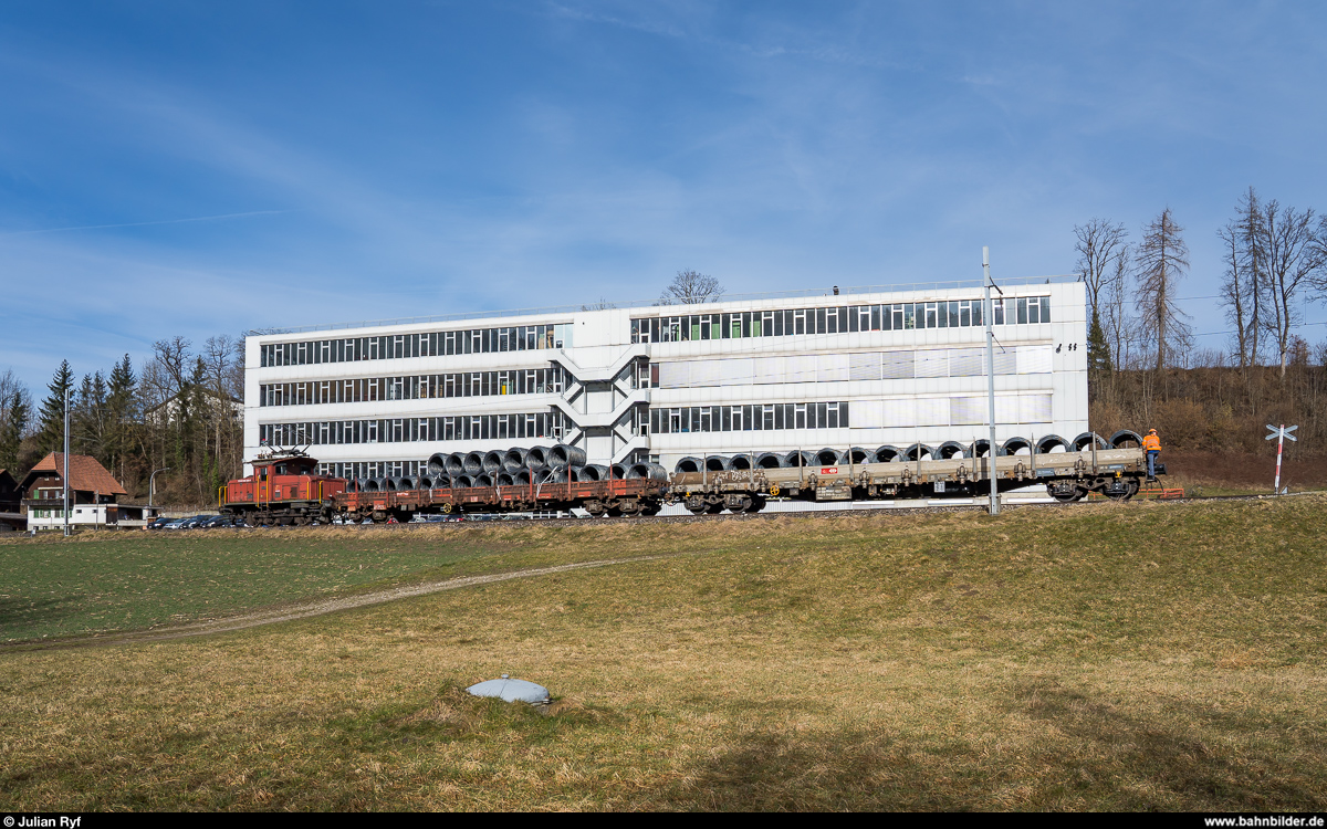 Die RUWA Drahtschweisswerk AG in Sumiswald besitzt zwei Ee 3/3, welche sie für die Überfuhr der von SBB Cargo in Sumiswald-Grünen angelieferten Güterwagen zu ihrem Werk im Ortsteil Burghof an der nicht mehr für den Personenverkehr genutzten Strecke Richtung Wasen nutzt. Da die Entladerampe im firmeneigenen Anschlussgleis nur Platz für zwei Wagen bietet, werden die Wagen im Bahnhof Sumiswald-Grünen gelagert und von der Ee 3/3 jeweils paarweise ins Werk zum Entlad und danach gleich wieder zurück gebracht. Ich habe den morgendlichen Wagenwechsel am 20. Februar 2020 fotografisch dokumentiert.<br>
Eine knappe halbe Stunde nachdem die leeren Wagen in den Bahnhof gebracht wurden, kehrte die Ee 3/3 16408 mit zwei vollen Wagen wieder zurück. Hier zwischen den Ortsteilen Grünen und Ei vor dem Produktionsgebäude von PB Swiss Tools.
