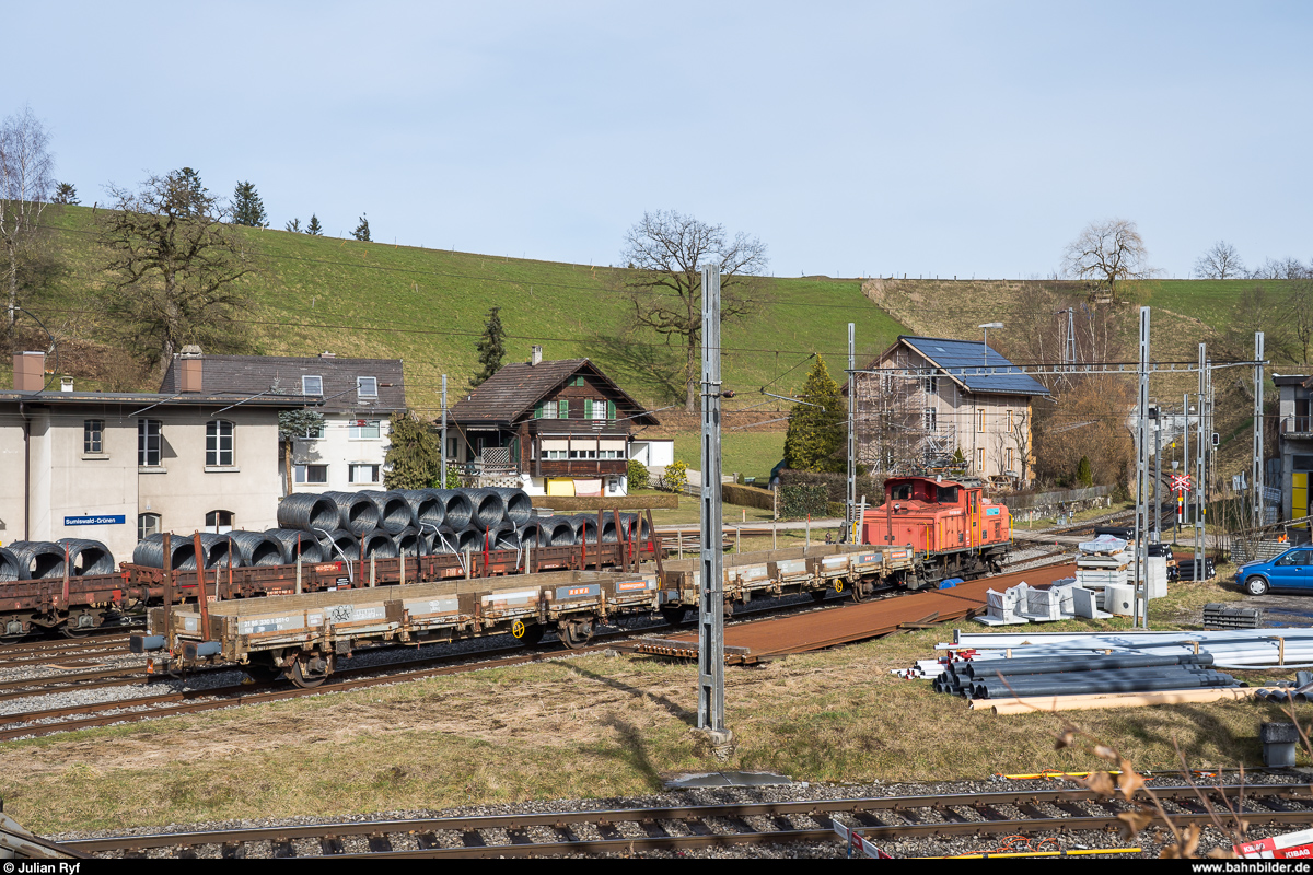 Die RUWA Drahtschweisswerk AG in Sumiswald besitzt zwei Ee 3/3, welche sie für die Überfuhr der von SBB Cargo in Sumiswald-Grünen angelieferten Güterwagen zu ihrem Werk im Ortsteil Burghof an der nicht mehr für den Personenverkehr genutzten Strecke Richtung Wasen nutzt. Da die Entladerampe im firmeneigenen Anschlussgleis nur Platz für zwei Wagen bietet, werden die Wagen im Bahnhof Sumiswald-Grünen gelagert und von der Ee 3/3 jeweils paarweise ins Werk zum Entlad und danach gleich wieder zurück gebracht. Ich habe den morgendlichen Wagenwechsel am 20. Februar 2020 fotografisch dokumentiert.<br>
Die hier im Bahnhof Sumiswald-Grünen abgestellte Ee 3/3 16403 von 1945 ist bereits einige Jahre bei der RUWA im Einsatz. Es ist zu vermuten, dass sie durch die neu übernommene Ee 3/3 16408 von 1946 überflüssig geworden ist und wohl bald ausgemustert wird. Dahinter steht ein am Vorabend eingetroffener Ganzzug mit Drahtrollen, welche an diesem Tag ins Werk müssen.
Das Gleis im Vordergrund führt zur RUWA-Fabrik und weiter nach Wasen, im Hintergrund geht es weiter nach Affoltern-Weier und Huttwil. Auf beiden Strecken gibt es seit mehreren Jahren keinen planmässigen Personenverkehr mehr und die Infrastruktur gehört der privaten Emmentalbahn (<a href= http://www.etb-infra.ch/de/ >http://www.etb-infra.ch/de/</a>).