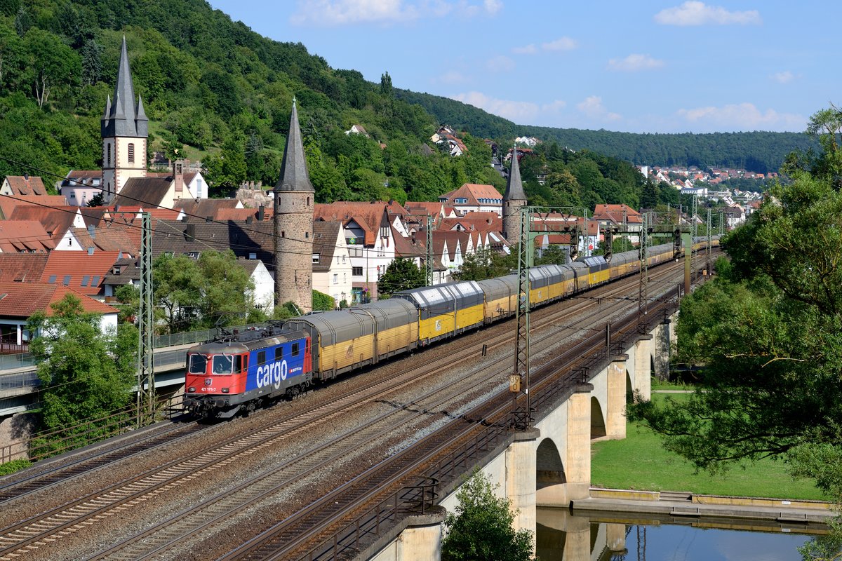 Die SBB Cargo 421 373 war am 18, Juli 2014 für den DGS 75738 von Dingolfing nach Bremerhaven Kaiserhafen eingeteilt. Hier passiert sie mit ihrem langen Autotransportzug die Stadt Gemünden am Main.