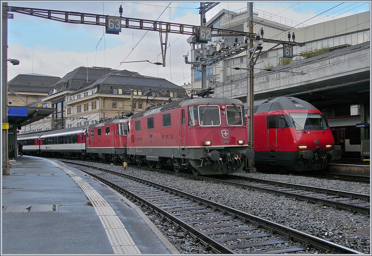 Die SBB Re 4/4 II 11197 (UIC 91 85 4420 197-6 CH-SBB) und Re 4/4 II 11199 (UIC 91 85-4420 199-2 CH-SBB) stehen im Lausanne mit einem Leermaterialpark auf Gleis  . Vom IR nach Luzern, der auf Gleis 1 eingefahren ist, ist nur die Spite der führende Re 460 zu sehen. 

14. Jan. 2019   