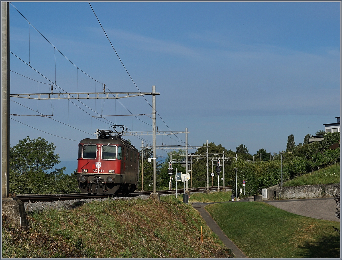 Die SBB Re 4/4 II 11245 (Re 420 245-1) auf der Fahrt in Richtung Palézieux kurz nach La Conversion, dessen Einfahrsignale im Hintergrund noch zu sehen sind.

14. Juli 2020
