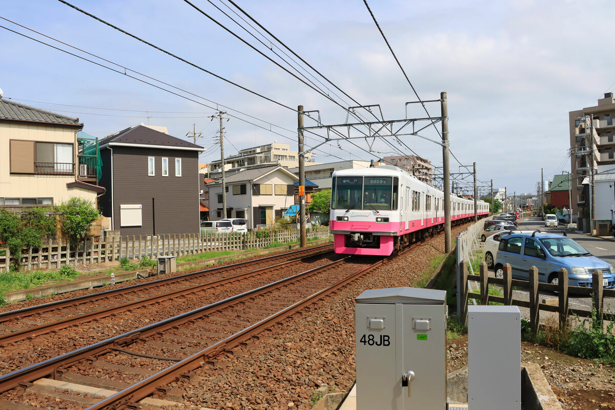 Die Shin Keisei Bahn: Diese etwa 27 km lange Bahn im Osten von Tokyo mit ihren bemerkenswerten rosaroten Zügen (1435 mm Normalspur) schlängelt sich durch merkmalloses Gebiet am Rande zwischen Schlafstadt und Bauernland. Noch ist es recht kompliziert, nach Tokyo hereinzugelangen, doch die Entwicklung der Bodenpreise zeigt an, dass sich das ändern wird, und das Gewirr von kleinen und grossen Häusern verdichtet sich allmählich. Im Bild Zug 8809 aus einer Triebzugserie von 1986-1991. Takane Kido, 28.April 2022 