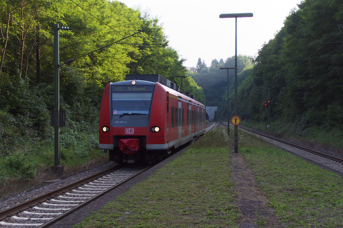 Die Sonne erreicht am Abend des 07.09.2014 den Einschnitt beim Bildstock Tunnel nicht mehr. 426 021 als RB Saarbrücken - St. Wendel fährt gleich in den Hp Bildstock ein. 
In Höhe des Tw befand sich links das Portal des alten Bildstock Tunnels. 1955 wurde die Strecke aus bergbautechnischen Gründen verschwenkt und ein neuer Tunnel gebaut.
Der alte Tunnel hatte eine Länge von 481 Metern, der neue hat nur noch 341 Meter. Bahnstrecke 3511 Bingen Hbf - Saarbrücken Hbf.
