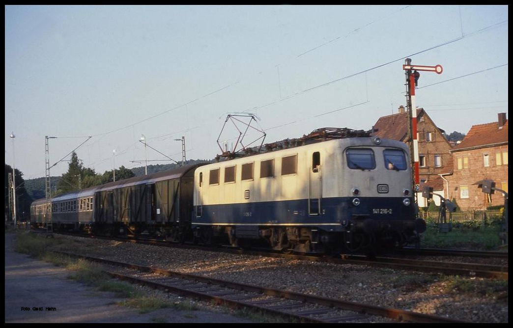 Die Sonne steht schon sehr tief, als 141216 mit dem E 3216 nach Neckarelz am 15.8.1989 um 19.13 Uhr in den Bahnhof Dallau einfährt. Hinter der Lok läuft ein alter Behelfspackwagen.