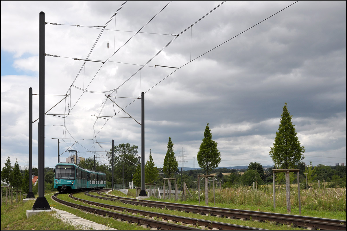 Die Stadtbahn über den Riedberg -

Um das große Neubaugebeit in Frankfurt-Riedberg mit Uni-Campus zu erschließen wurde eine neue 3,8 km lange oberirdische Stadtbahnstrecke mit zwei Stationen gebaut und 2010 eröffnet. Die Strecke verbindet die bestehenden Haltestellen Niederursel an der U3 mit Kalbach an der U2 und wird von den Linie U8 und U9 befahren.

Nach der ursprünglichen Planung war sie Teil einer vierten Stammstrecke (D) der Frankfurter U-Bahn. Diese sollte im Endausbau von Schwanheim über den Hauptbahnhof, Ginnheim, Nordweststadt, Riederberg nach Bad Homburg führen. Nur drei Abschnitte dieser Strecke wurden bislang realisiert. Für die Nordweststadt und auch Riedberg wäre aber zumindest ein Lückenschluss zwischen Bockenheimer Warte und Ginnheim sehr sinnvoll.

Hier ein Blick auf die Strecke zwischen den Stationen Uni-Campus Riedberg und Niederursel.

12.07.2017 (J)

