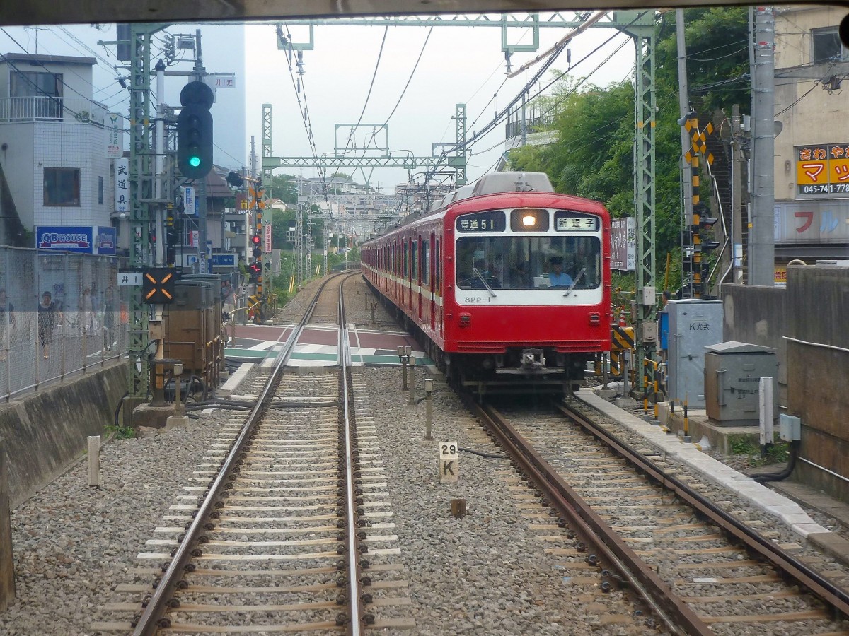 Die Stammstrecke des Keihin Kyûkô (Keikyû)-Konzerns: Hier geht es noch ebenerdig durch das enge Häusermeer. Zug 822 (Serie 800) kommt bei Kami Ôoka entgegen, 25.Juni 2011. 