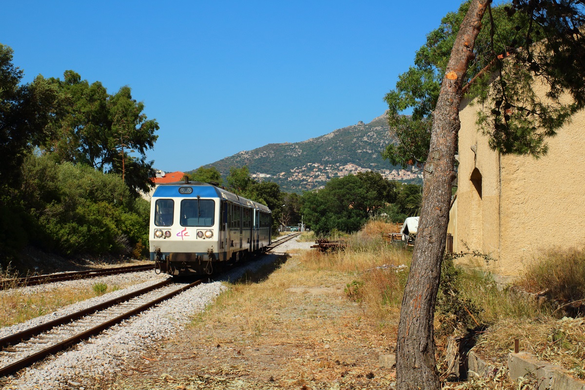 Die Strandbahn von L'Ile-Rousse nach Calvi mit X 97051 an der Spitze fährt am 09.06.2014 in den Bahnhof Calenzana-Lumio ein. Nach Lumio, dem im Hintergrund sichtbaren Ort am Berghang, sind es von hier aus allerdings noch einige Kilometer.