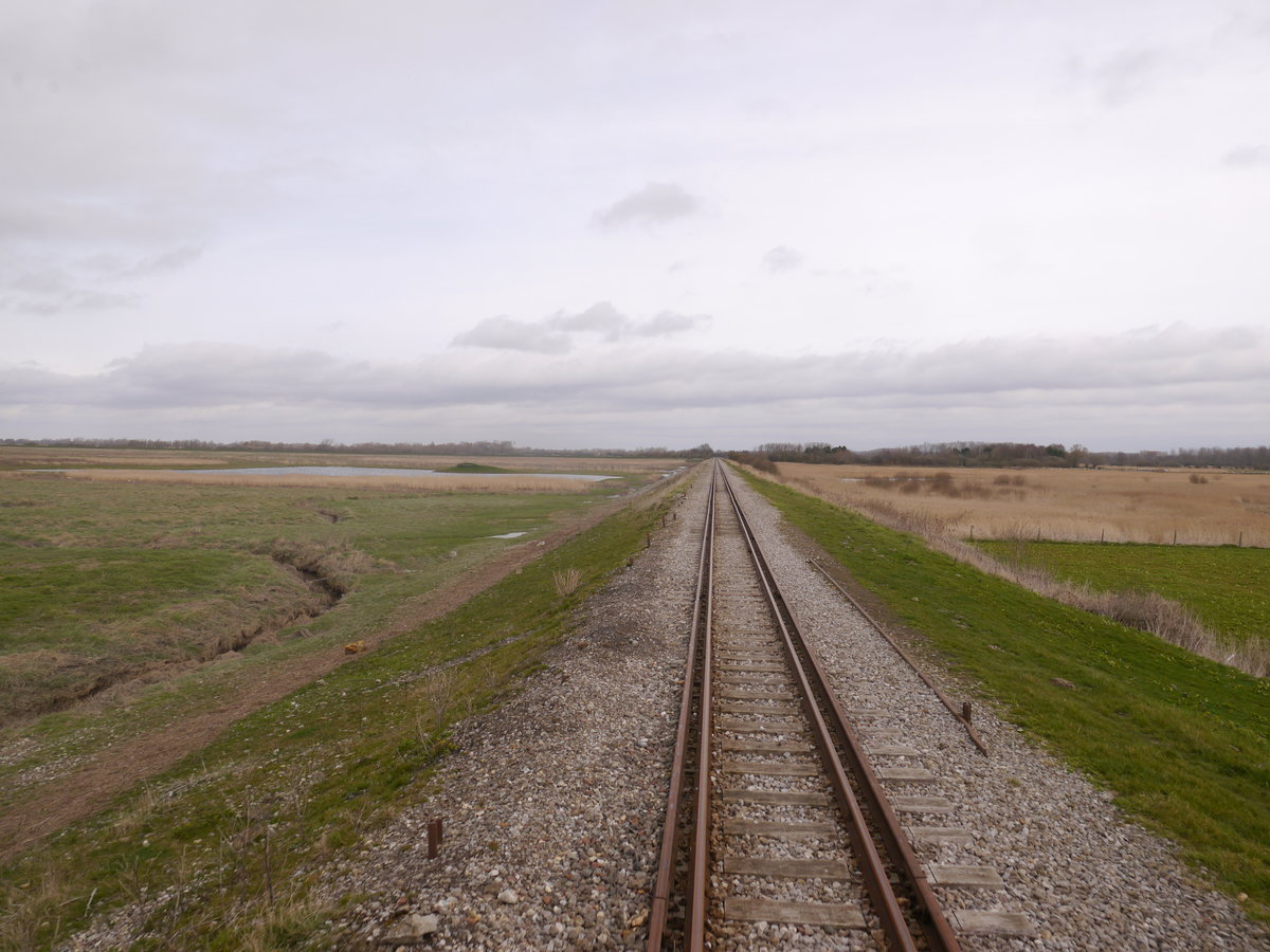 Die Strecke der Chemin-de-Fer-de-la-Baie-de-Somme (CFBS) ist von Noyelles-sur-Mer bis nach St.Valery-sur-Somme-Port viergleisig und mit Meterspur- und Normalspurfahrzeugen befahrbar. Früher diente dies dazu, dass der Hafen St.Valery-sur-Somme auch mit normalspurigen Wagen erreichbar war. Das Vierschienengleis ist nach wie vor vorhanden. Die Normalspurgleise erlauben es heute die Werkstatt der CFBS auch mit Regelspurfahrzeugen zu erreichen und auch für Sonderfahrten werden sie sporadisch benutzt. Wir fahren hier auf den Meterspurgleisen Richtung St.Valery-sur-Somme.
Die Strecke führt hier auf einem Damm über die Niederung der Sommemündung.
Noyelles-sur-Mer 26.03.2016
