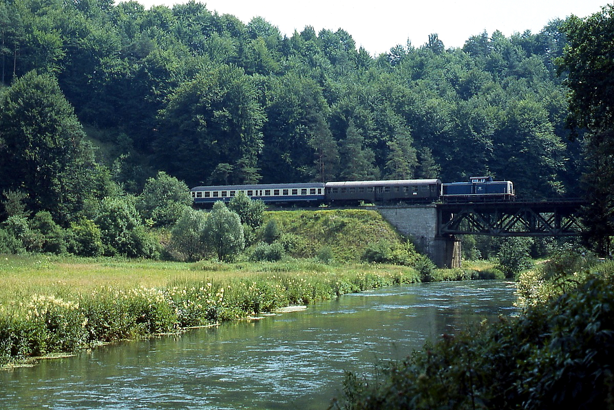Die Strecke durch das Pegnitztal bietet viele schöne Fotomotive. Im Juli 1985 überquert eine 212 mit einem kurzen Nahverkehrszug zwischen Velden und Rupprechtstegen die Pegnitz.