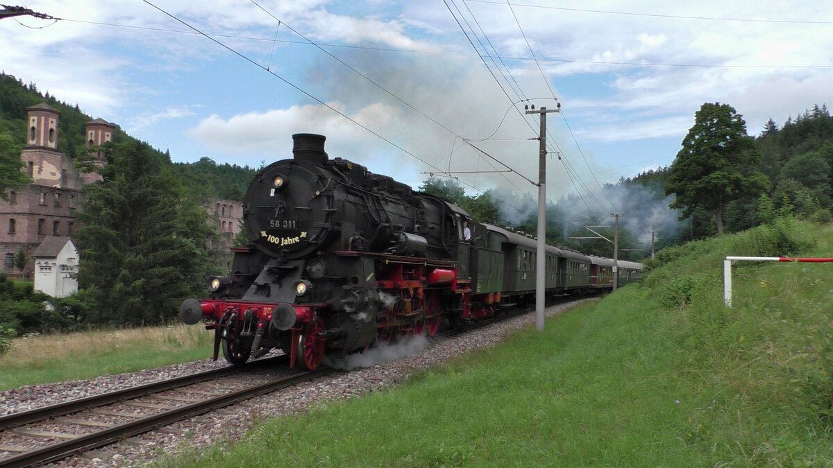 Die Ulmer Eisenbahnfreunde sind am 25.07.2021 mit 58 311 auf der Albtalbahn unterwegs. Hier dampft die erste Fahrt des Tages durch Frauenalb in Richtung Bad Herrenalb. Im Hintergrund ist die Klosterruine Frauenalb zu sehen.