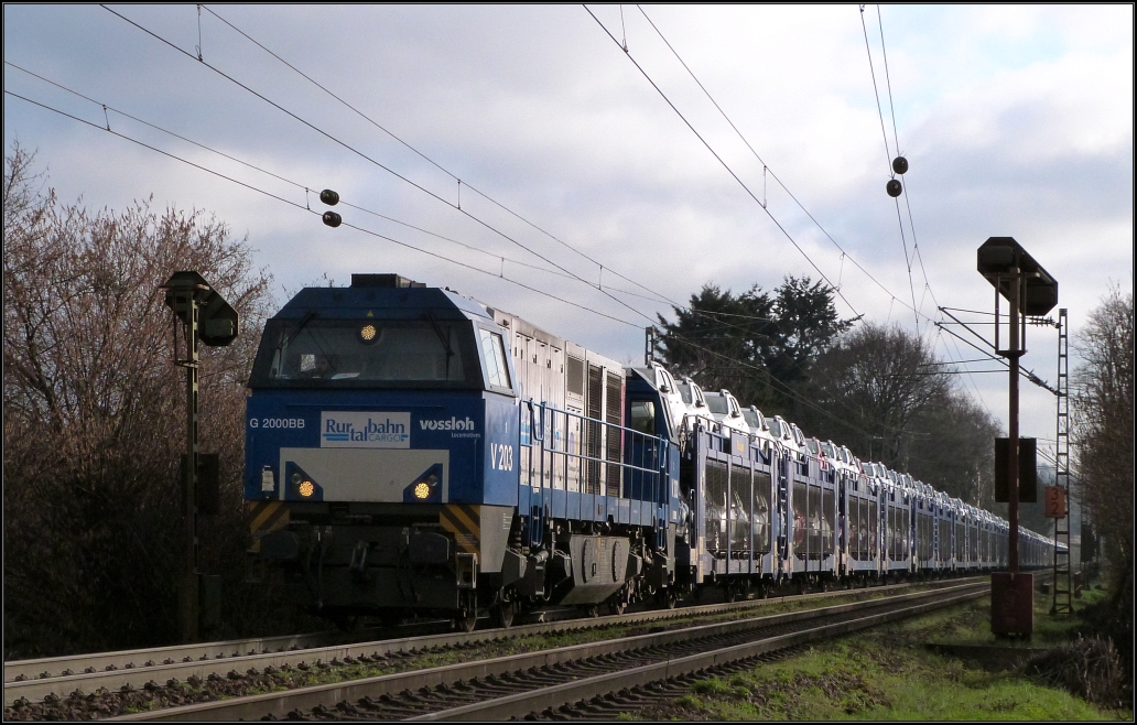 Die Vossloh G 2000 BB der Rurtalbahn ist mit einen Dacia Autotransportzug am Haken nach Belgien unterwegs. Hier zu sehen unweit von Aachen auf der Montzenroute am Gemmenicher Weg am Morgen des 06.April 2016. Nette Grüße retour an den Tfz.