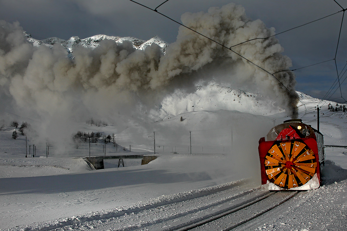 Die weltweit einigzartige,prächtige Dampfschneeschleuder Xrod d9213 präsentiert ihre wunderfeine Rauchfahne am Berninapass oben bei starkem Wind und herrlichem sehr kaltem Winterwetter,kurz vor dem Bahnhof Hospizia Bernina.Bild vom 25.1.2015